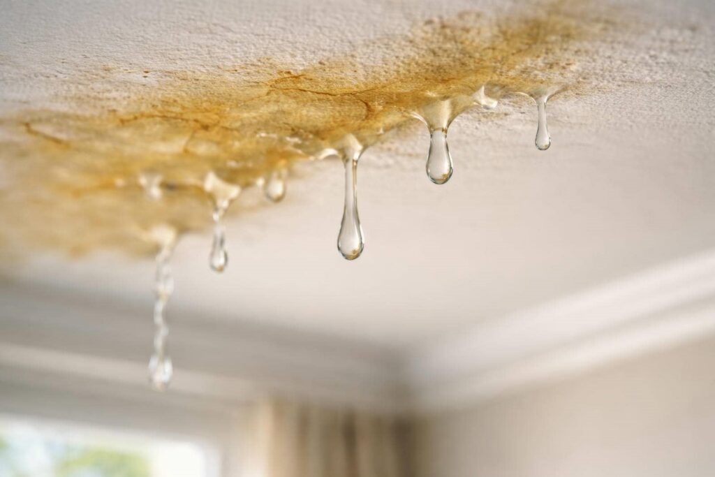 Water droplets leaking from a ceiling with visible brown water stains.
